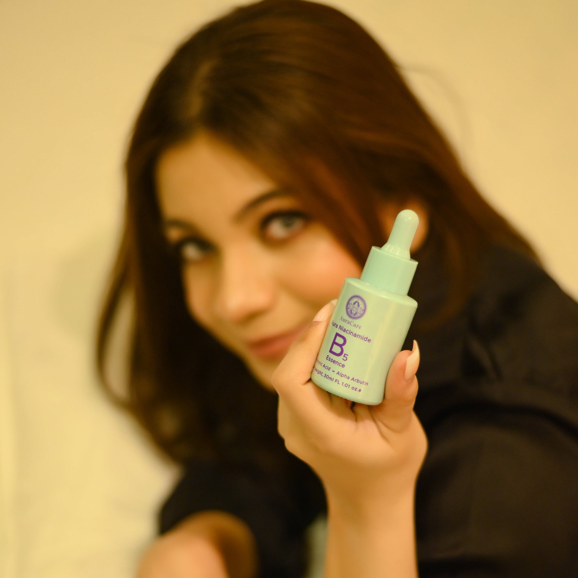 Woman holding a green skincare bottle with a dropper.