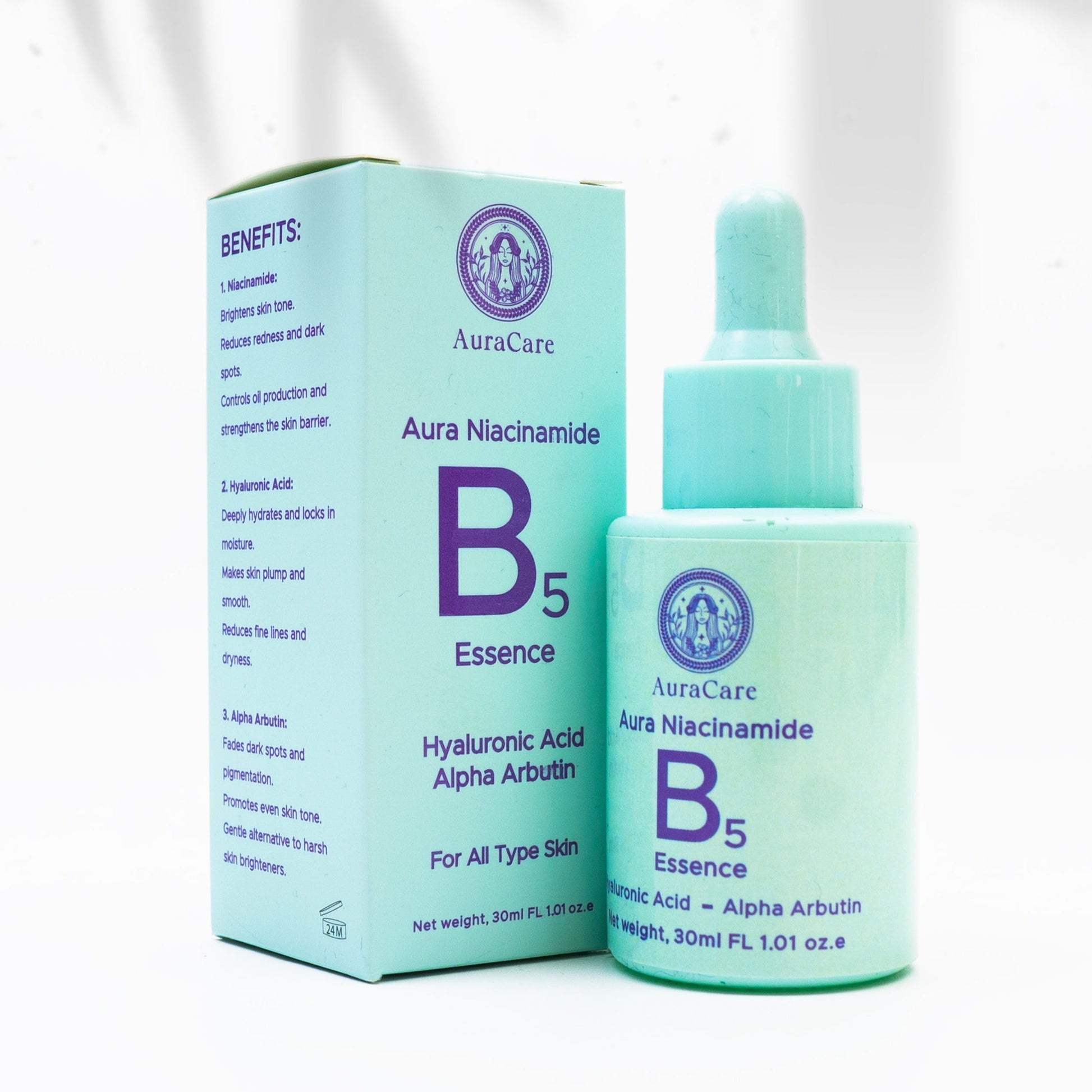 A product image featuring a bottle of Aura Niacinamide B5 Essence next to its packaging box, which is placed on a white surface with a shadow falling across the scene.